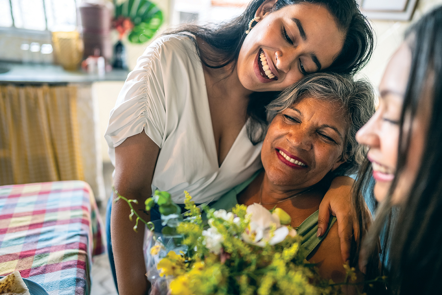 Young sisters giving flowers to grandmother at home